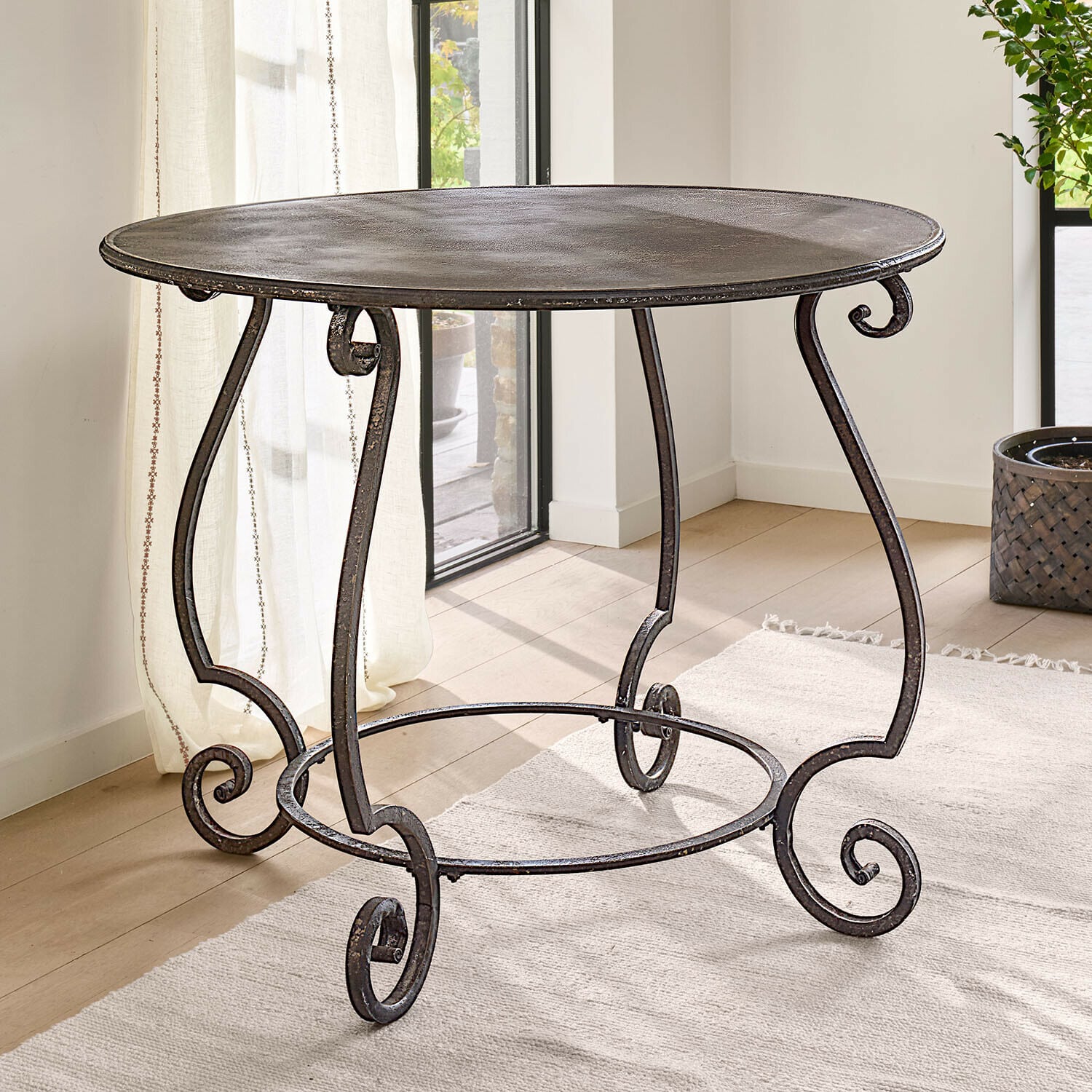 Ronde metalen tafel in donkerbruin met decoratieve poten en rustieke afwerking voor binnen