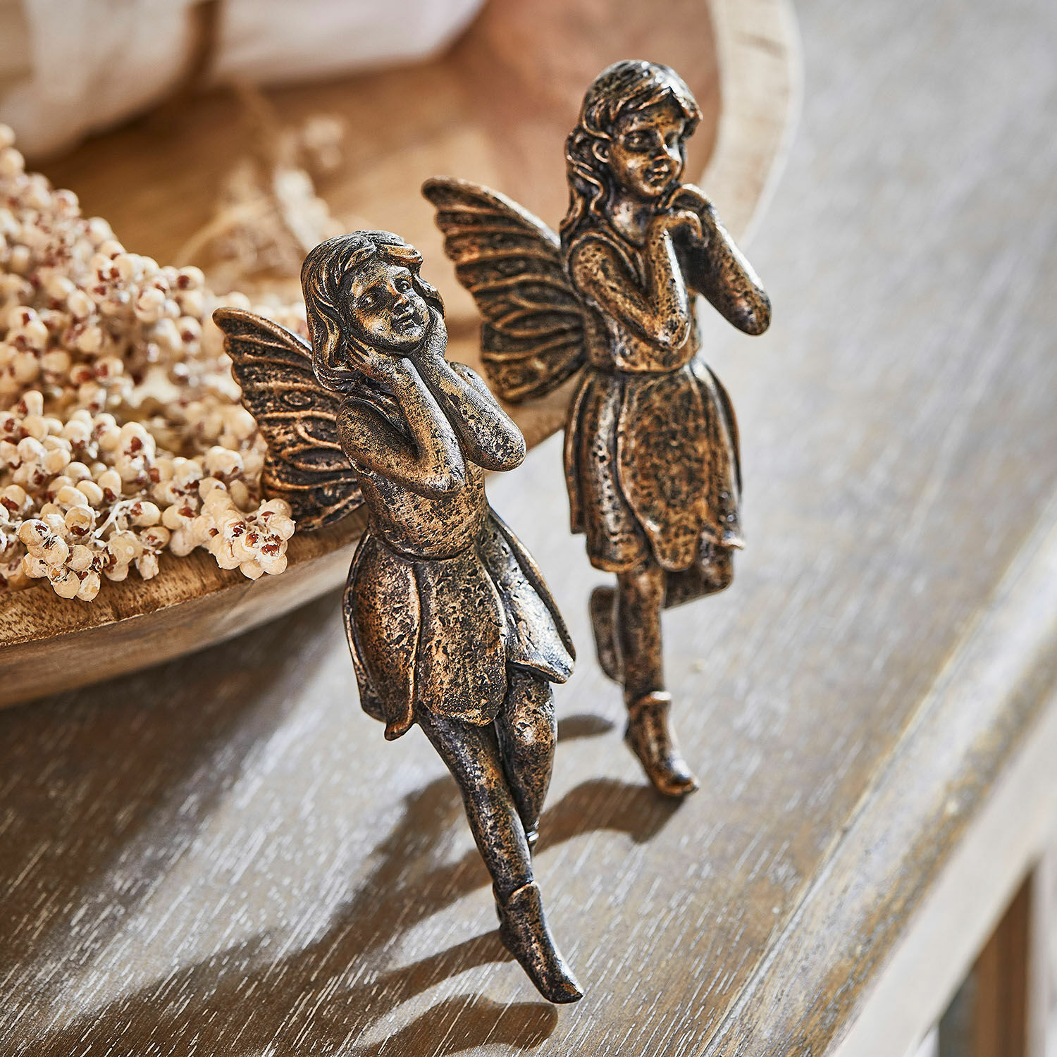 Twee decoratieve metalen feeënfiguren in antiek goud op houten tafel, interieurdecoratie