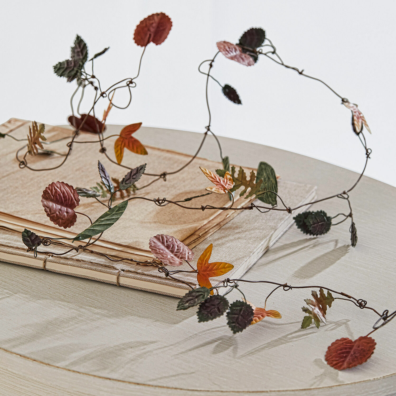 Guirlande Merel Decoratieve metalen slinger met gekleurde herfstbladeren op lichte tafel