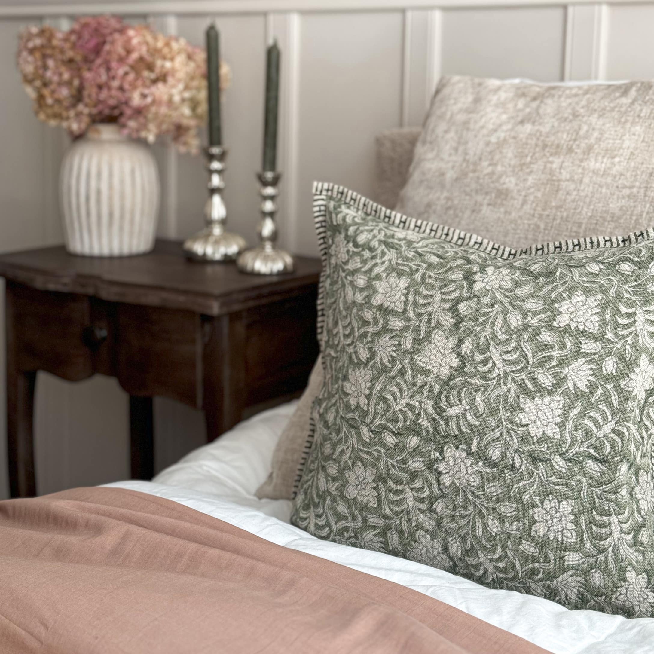 Decoratief kussen met groen bloemenpatroon op beige stof op een bed in vintage stijl