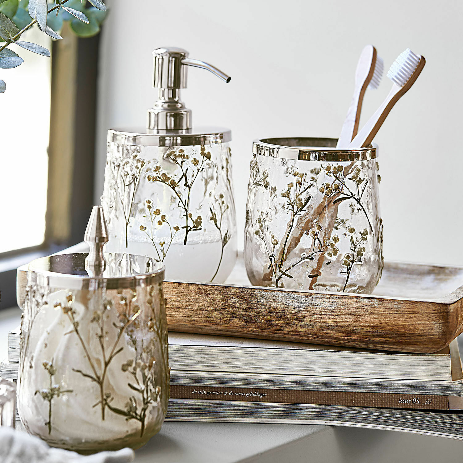 Glazen badkamer set met bloemenpatroon en metalen accenten op houten dienblad