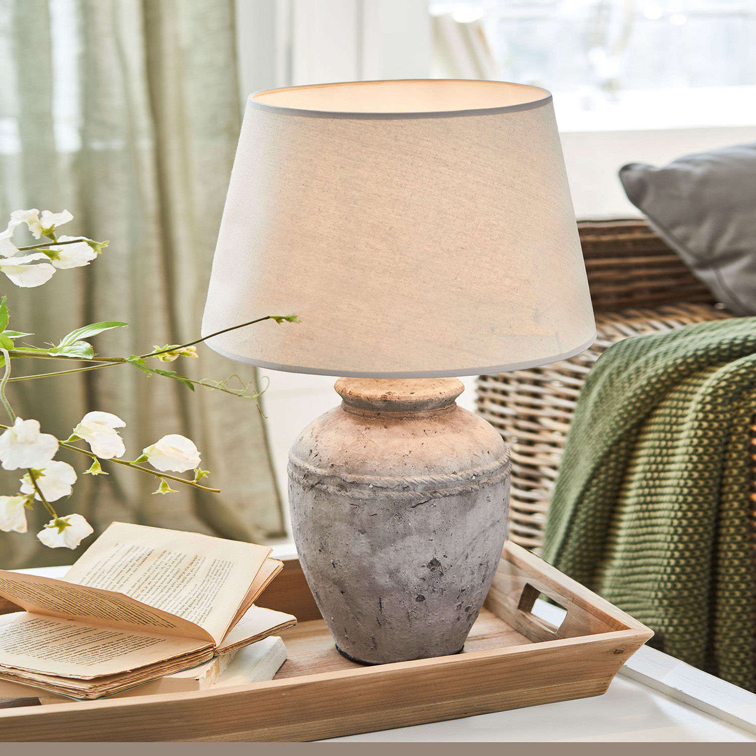 Tafellamp van grijze keramiek met beige kap op houten dienblad in woonkamer