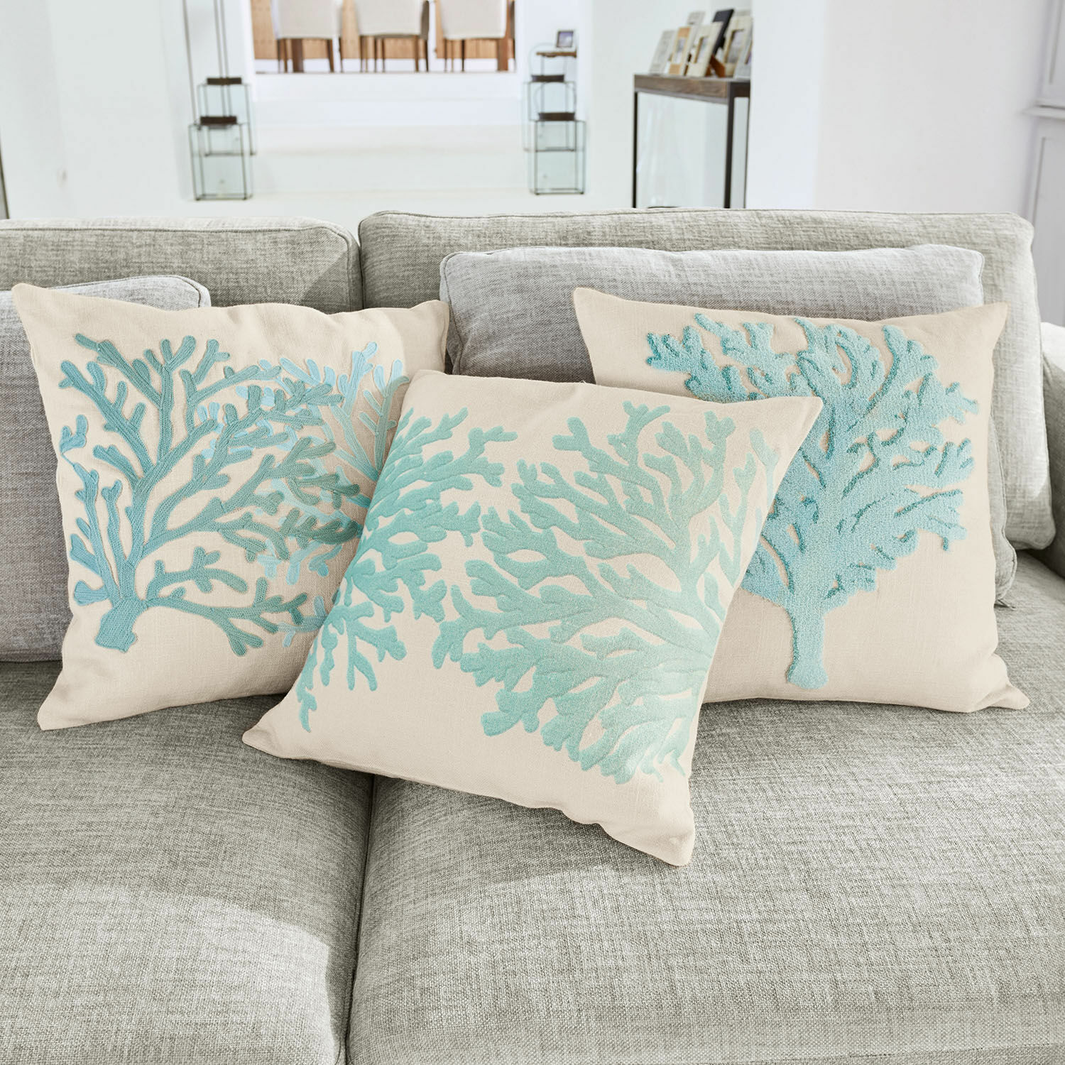 Kussenhoes set van 3 Vaiea Beige sierkussens met blauwe koraalborduursels op grijze bank voor woonkamer