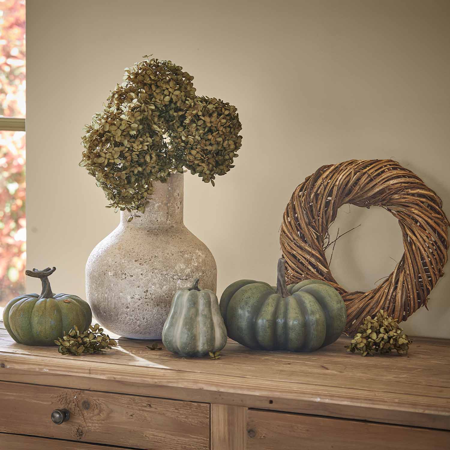 Steenvazen met gedroogde bloemen en groene pompoenen op een houten tafel als decoratie