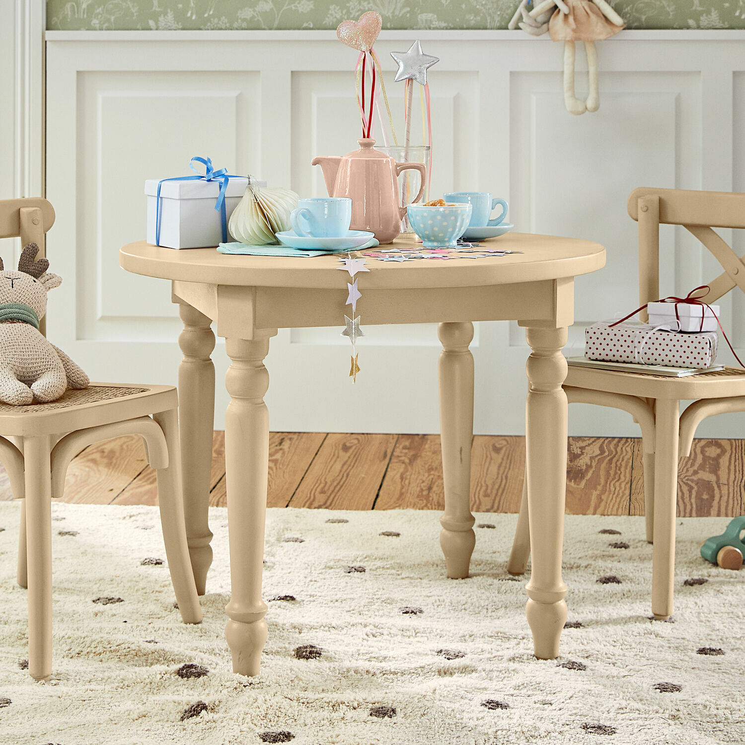 Kindertafel Sourila Beige ronde houten kindertafel met decoraties en speelgoed op een gestippeld tapijt