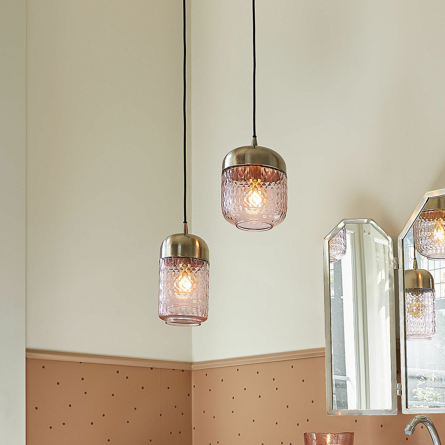Twee hanglampen van roze glas met metalen kappen in een modern interieur