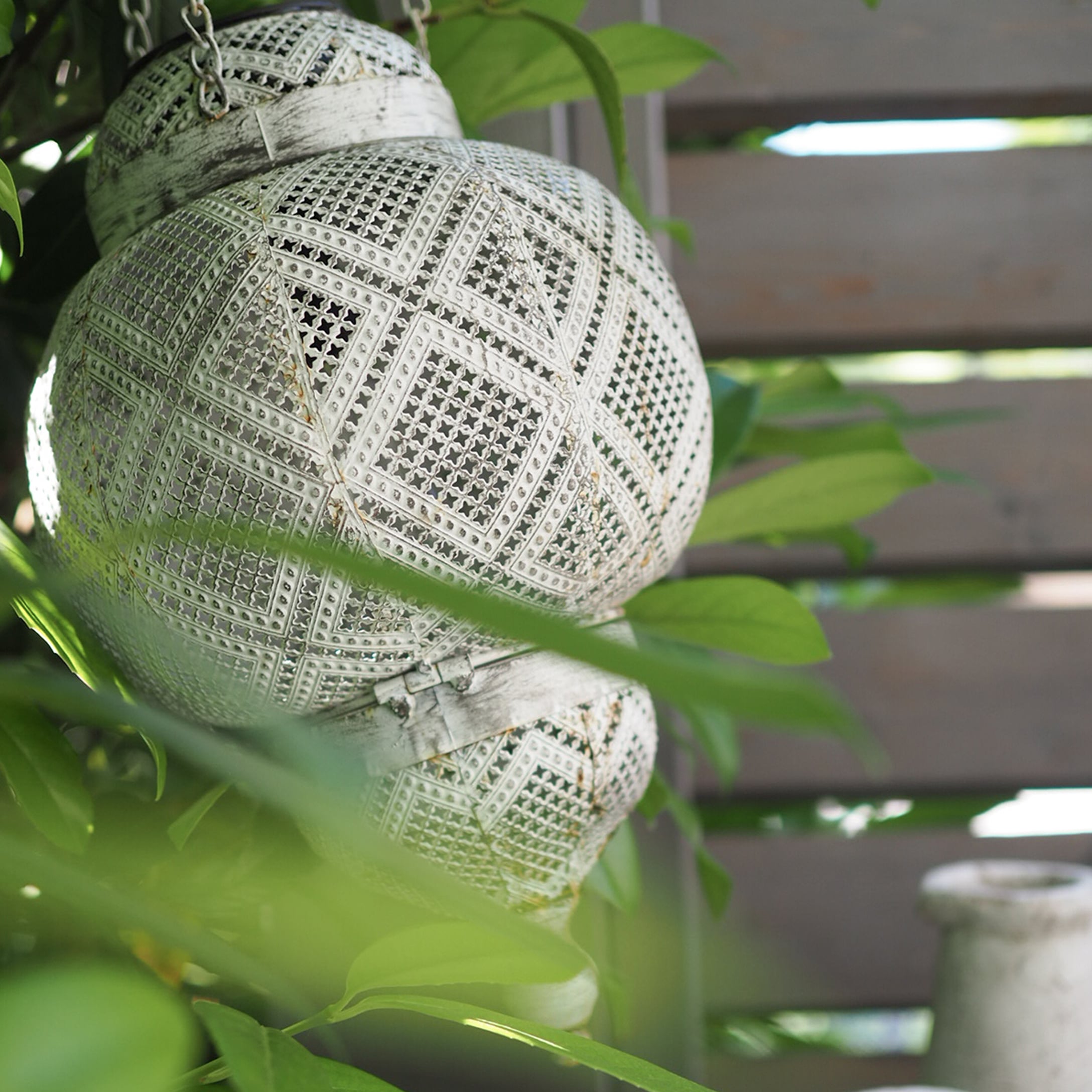 Witte metalen tuinlantaarn met decoratief geperforeerd patroon en ophanging