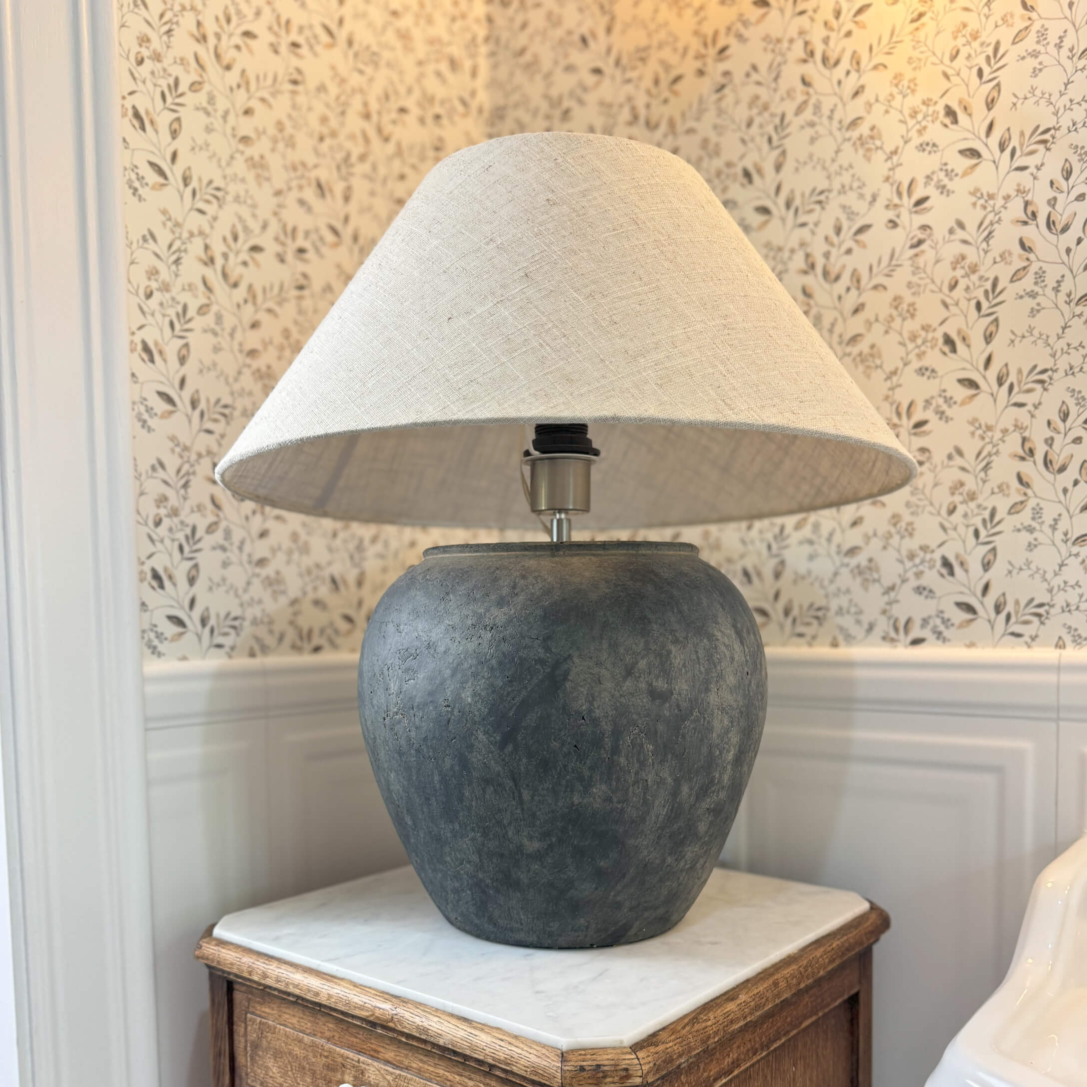 Tafellamp van donkergrijs keramiek met beige kap op houten tafel in klassieke kamer