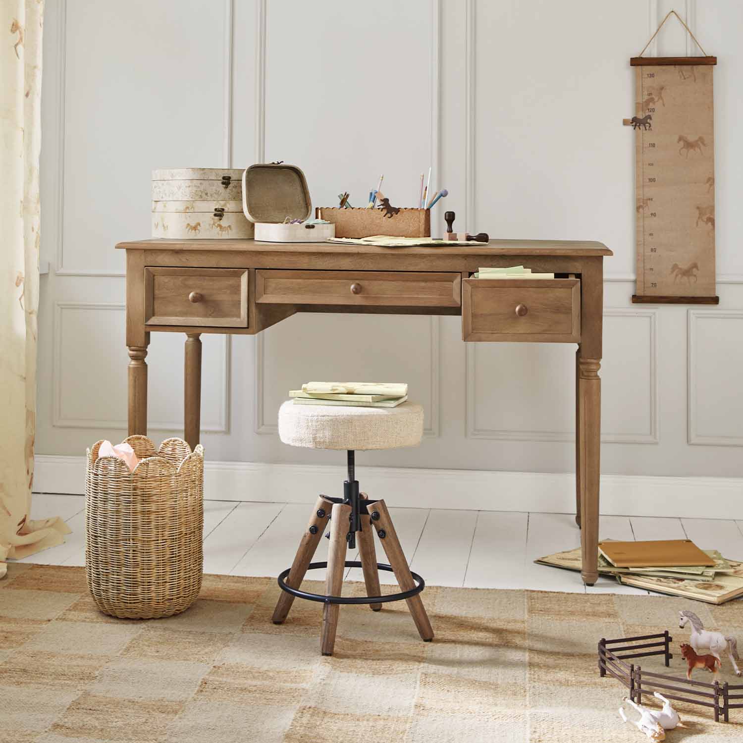Houten bureau met drie lades en beige kruk voor lichte muur met paardenmotief